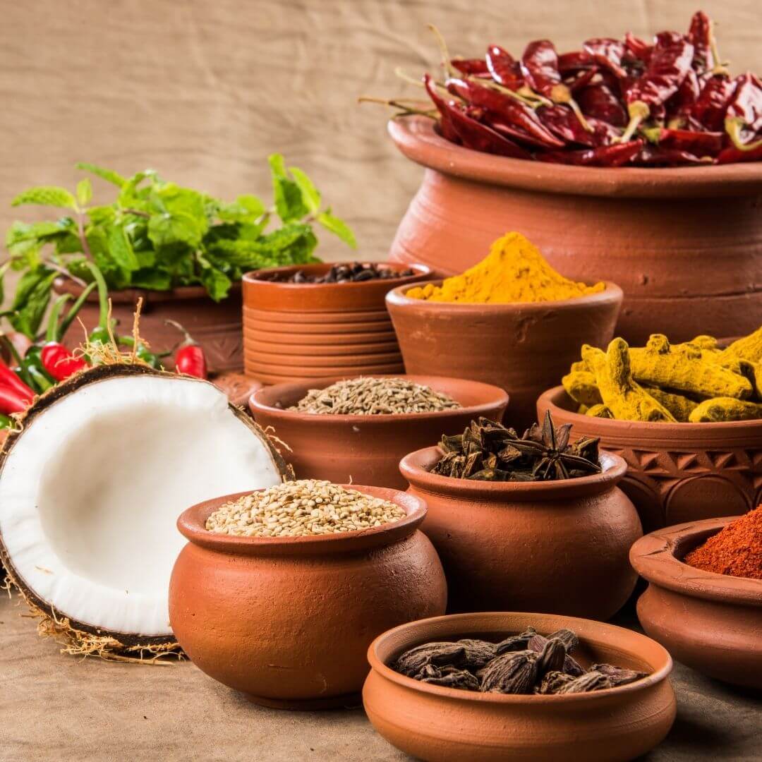 Premium spices including cardamom, cinnamon and cloves in earthen bowls