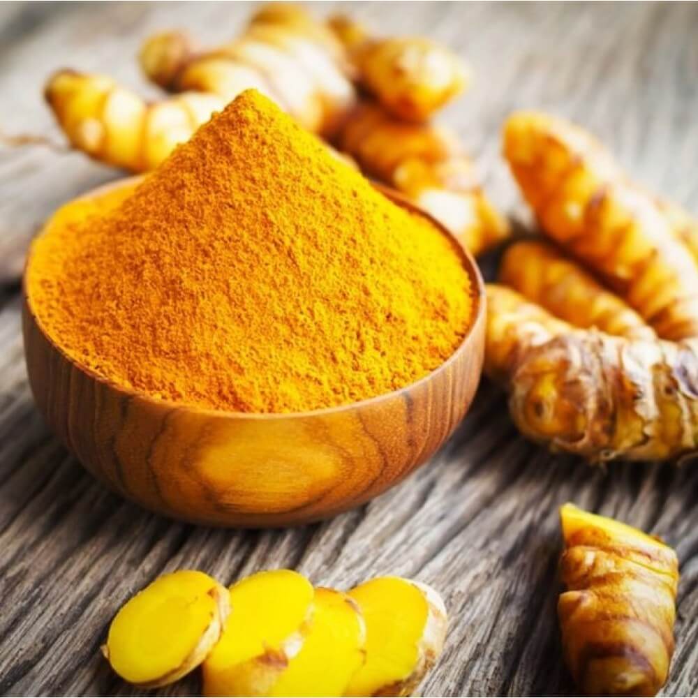 Vibrant bright orange turmeric powder with turmeric roots