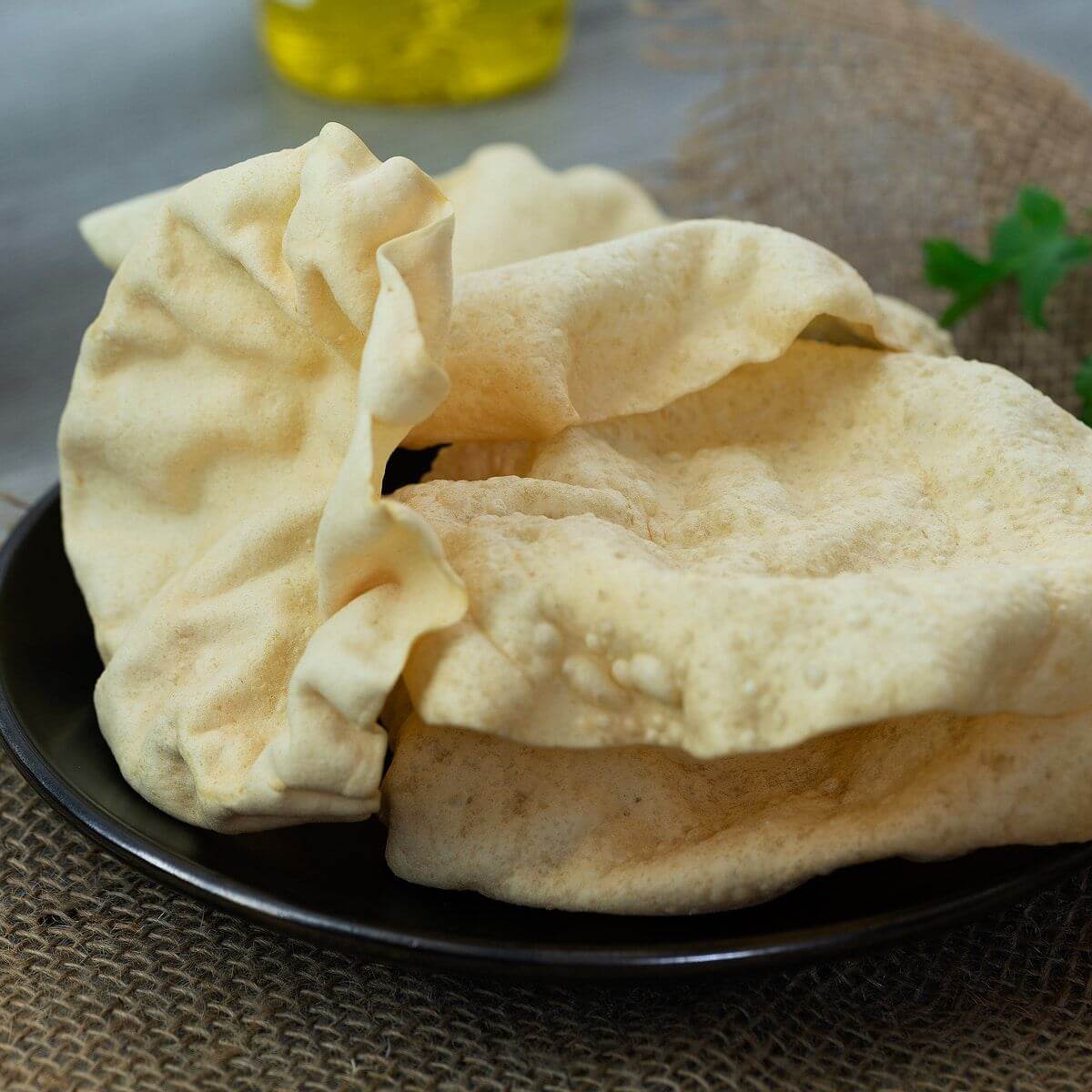 Stack of thin crispy round urad dal papads on a traditional wooden plate